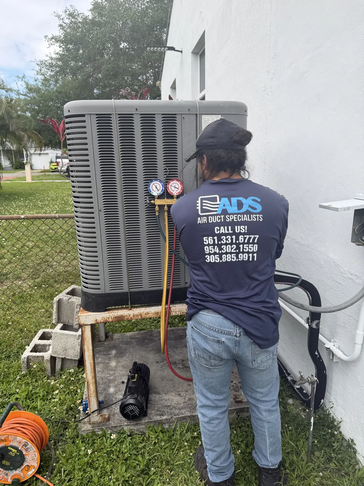 Air Duct Specialists LLC technician diagnosing AC unit with refrigerant gauges — South Florida
