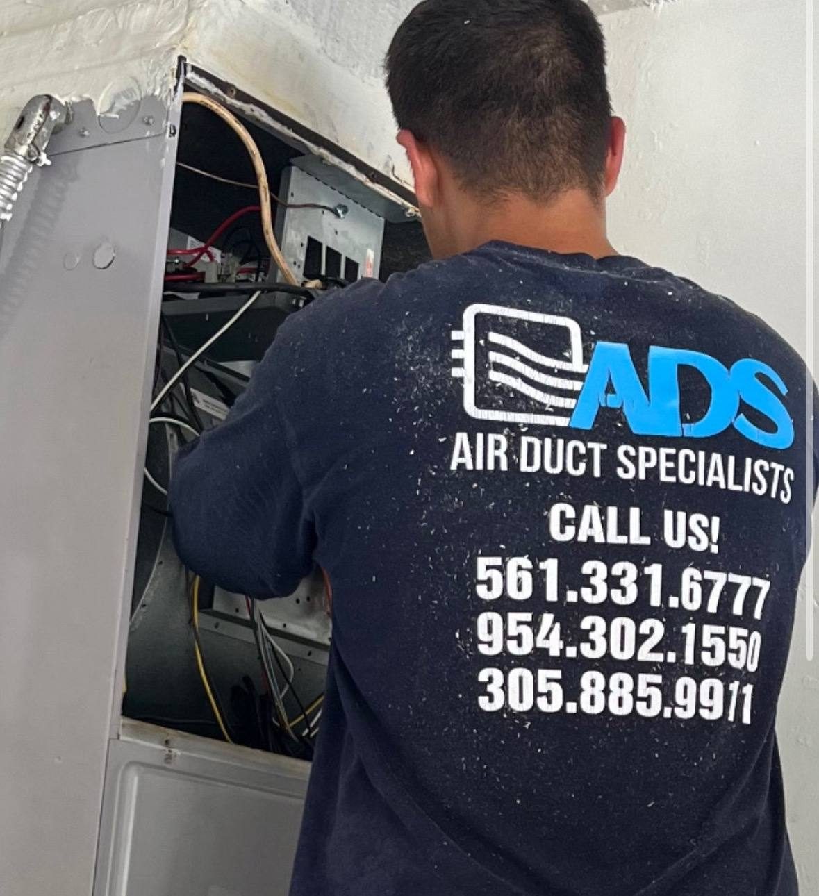 Air Duct Specialists LLC technician working inside an open air handler cabinet during a duct cleaning in South Florida