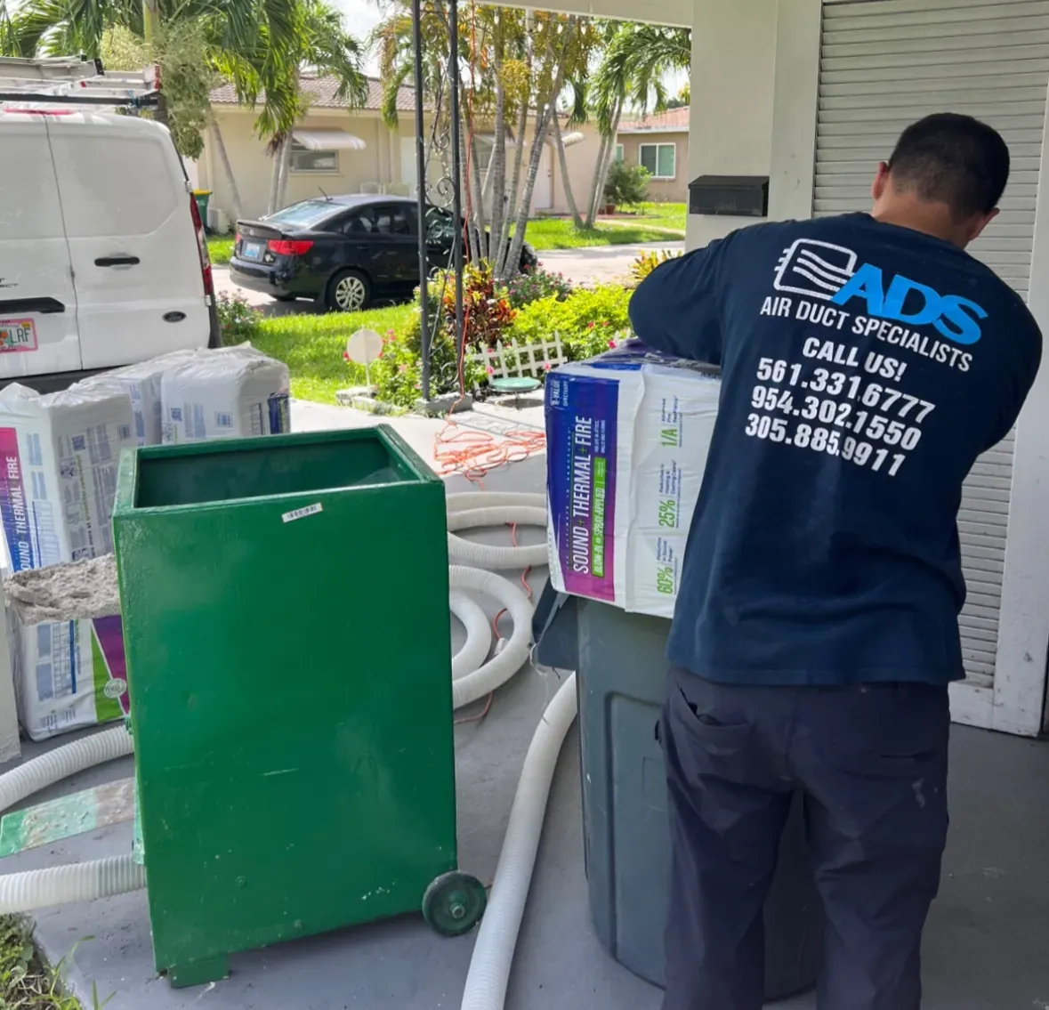 Air Duct Specialists technician loading blown-in insulation into a blower machine at a South Florida home