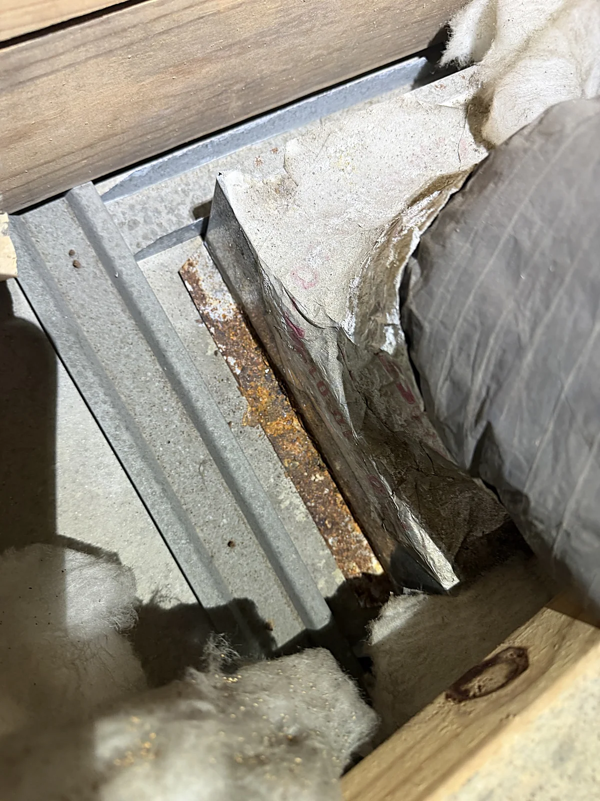 Close-up of an oxidized metal duct boot with rust from repeated condensation in a Coral Gables attic