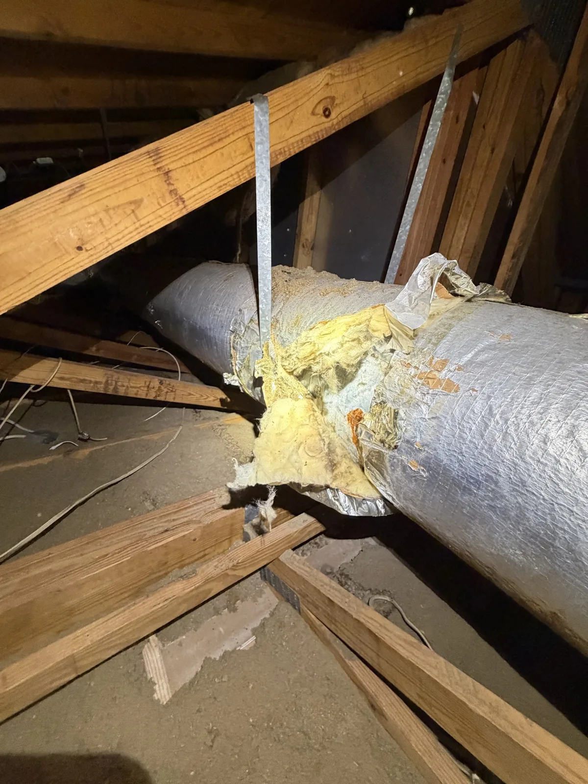 Ripped air duct in a Boca Raton attic with insulation exposed — Air Duct Specialists LLC