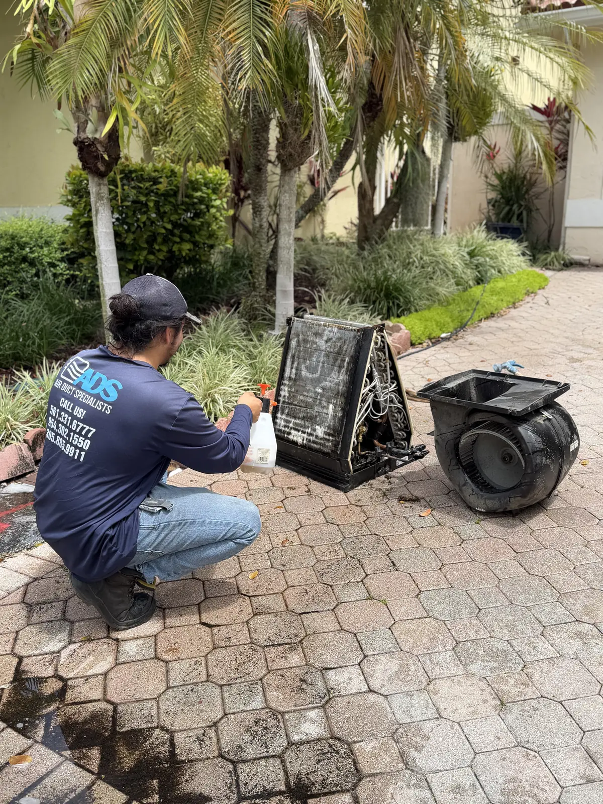 Air Duct Specialists LLC technician cleaning evaporator coil with blower motor removed — South Florida