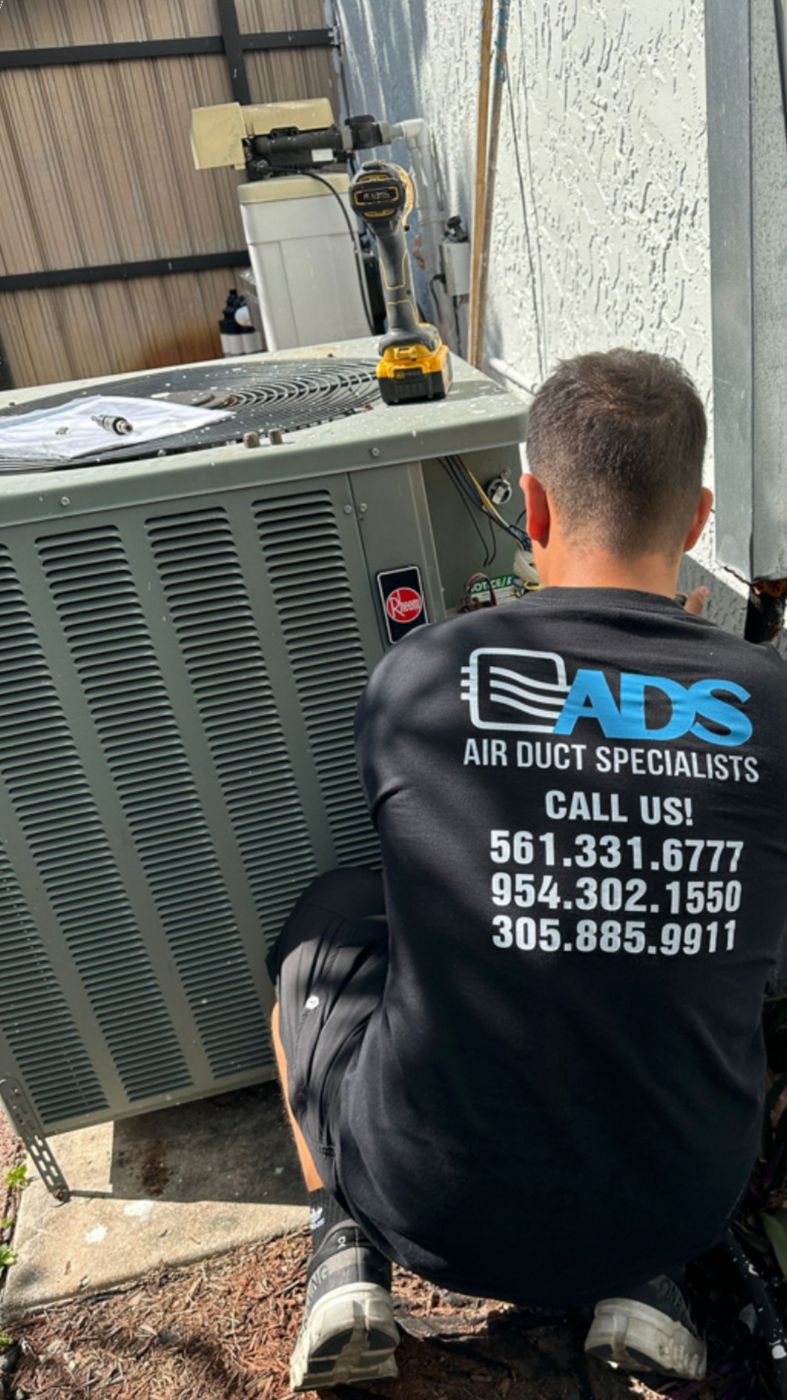 Air Duct Specialists technician diagnosing a residential AC condenser to advise repair or replacement in South Florida